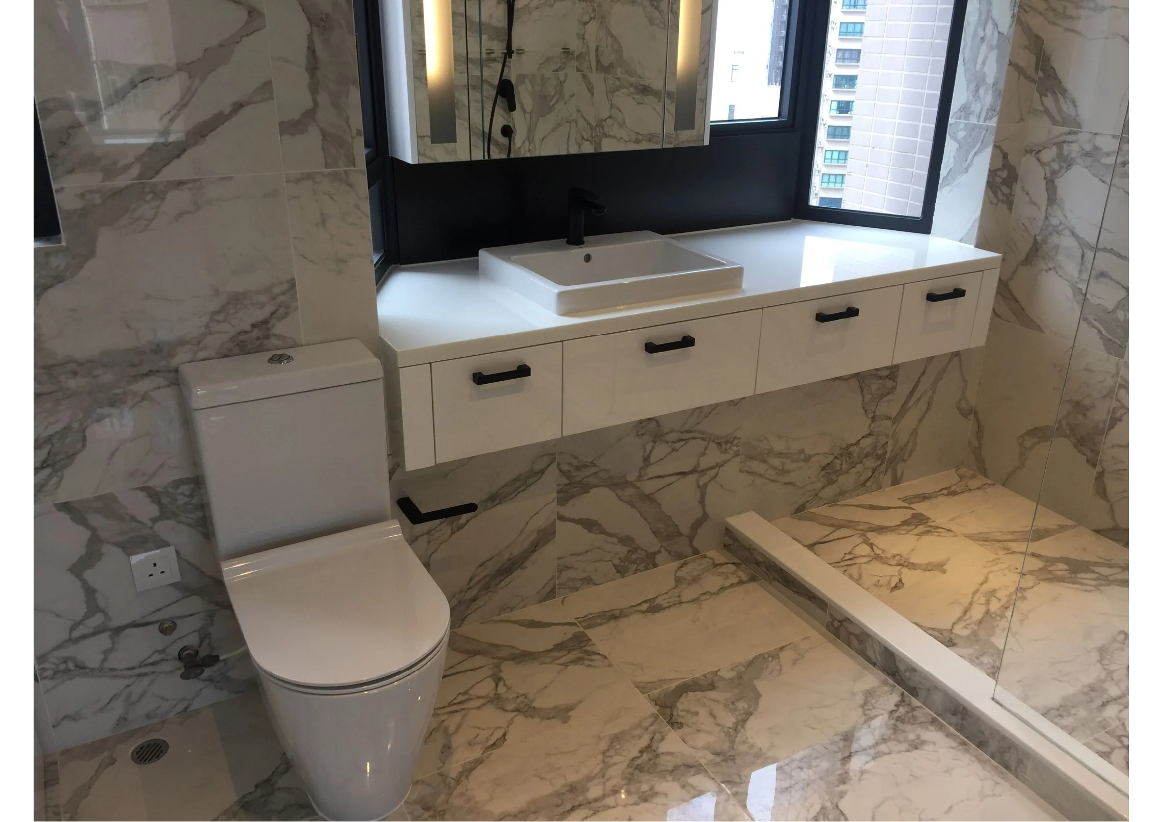 Central bathroom with a stone-clad shower, glazed screen and white vanity unit