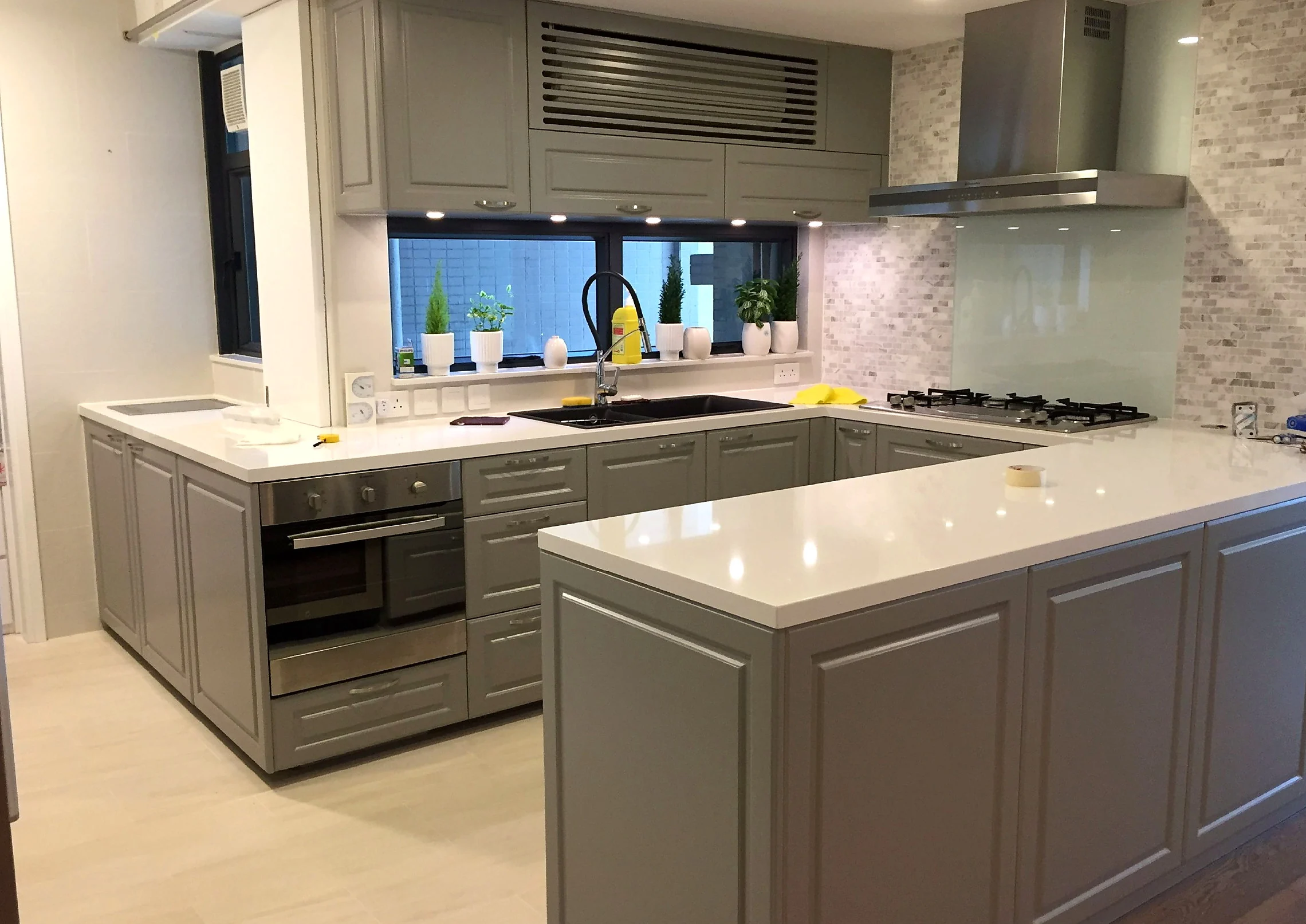 Grey cabinetry, pale worktops and an island in a Mid-Levels kitchen